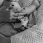 Photographie en noir et blanc d'un moment de douceur entre parent et enfant, accompagnement périnatalité et parentalité par Morgane Bessa à Limoges.